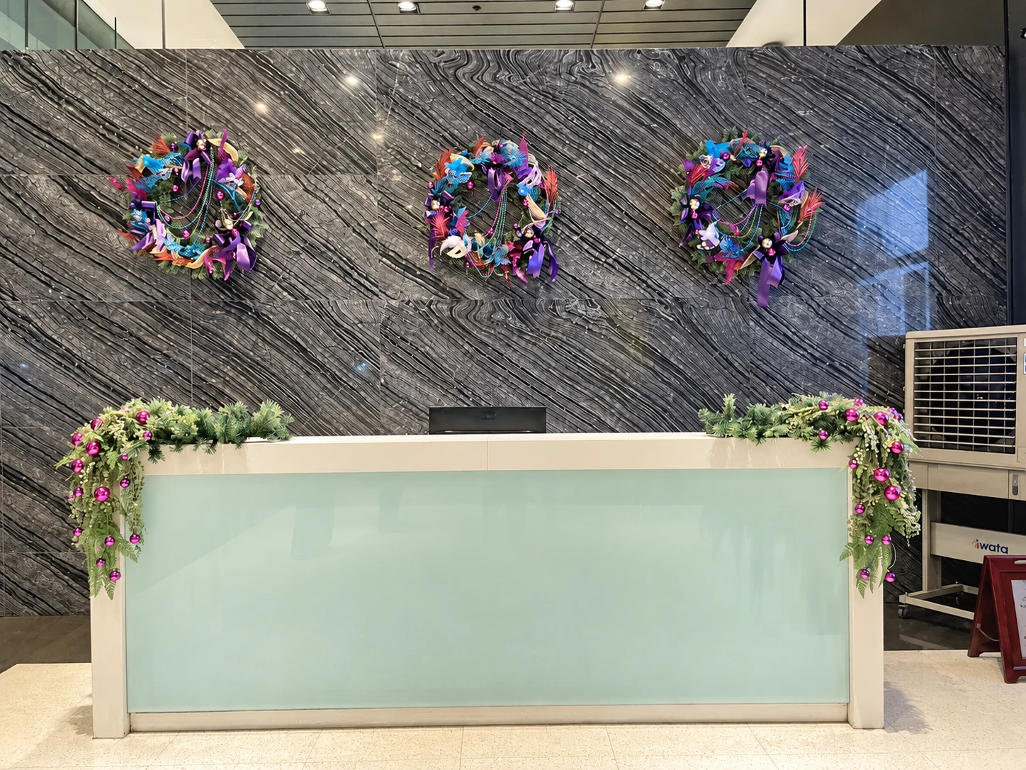 Three colorful wreaths and greenery at a reception desk